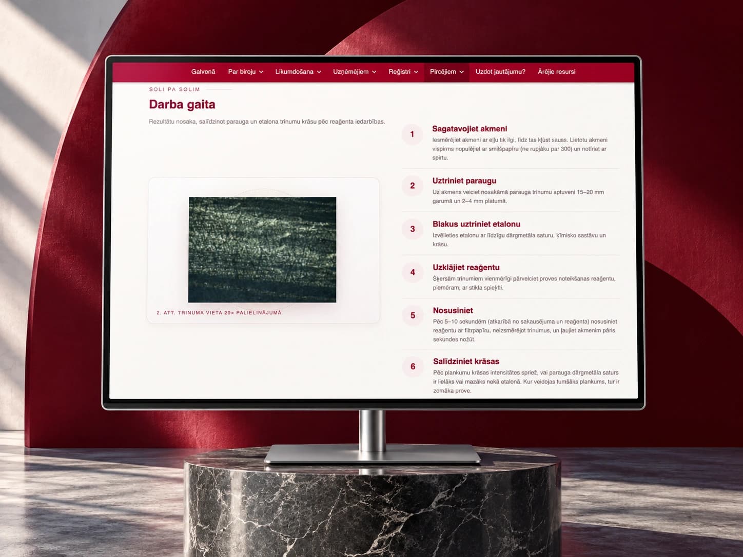 The prove.lv assaying guide on a monitor in a composition with a burgundy arc and marble.