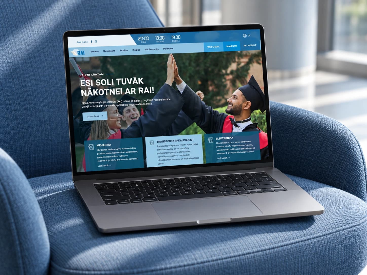 The rai.lv homepage on a laptop in a blue armchair.